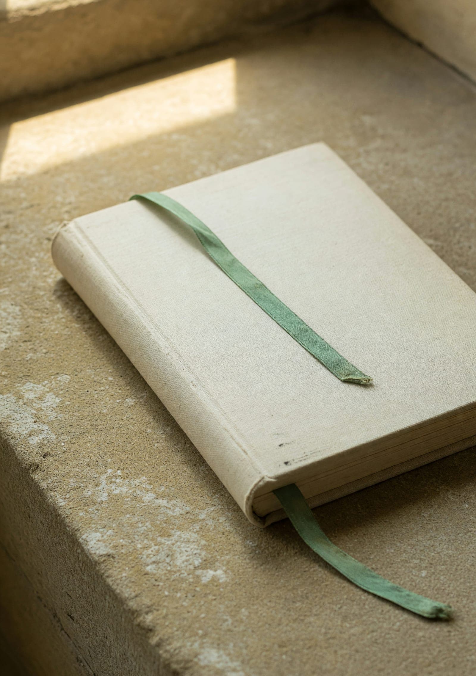 A linen-bound book resting on stone in soft light